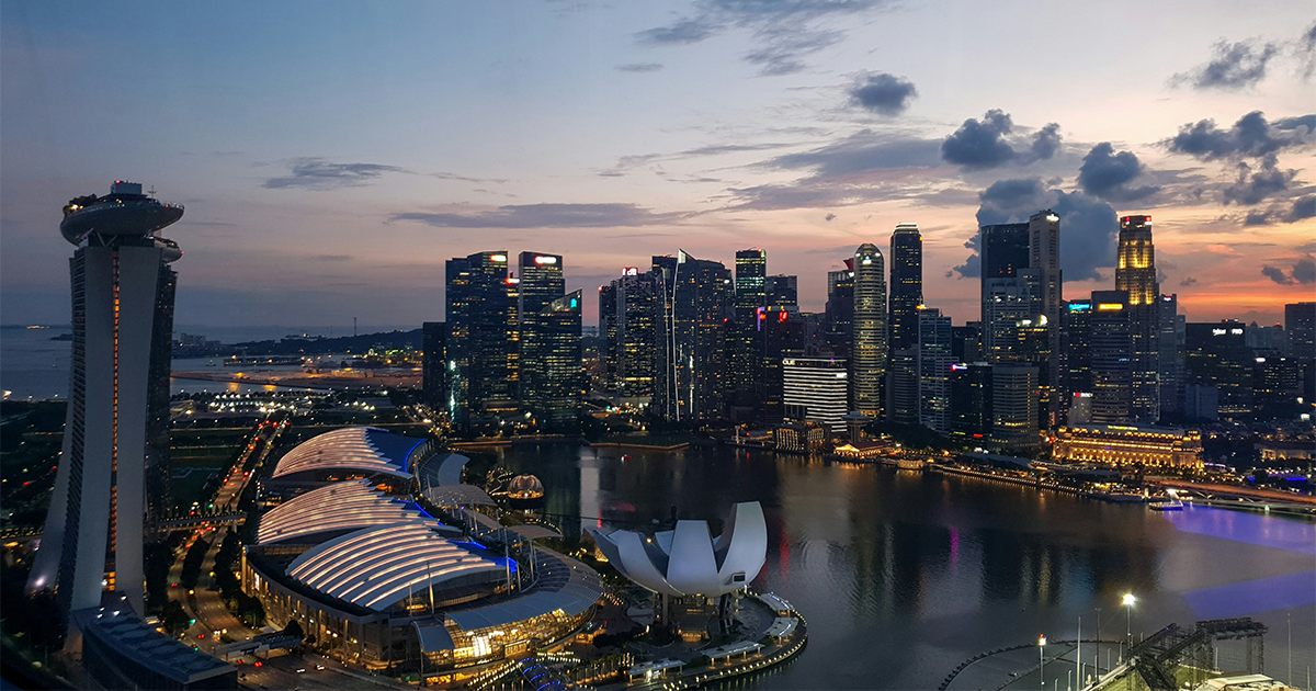 Dusk view of Marina Bay, with Marina Bay Sands on the left, the ArtScience Museum in the foreground, and Singapore’s illuminated skyline reflected in the bay.